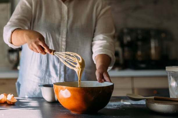 istock Anonymous Plus Size Female Baker Mixing Dough with a Whisk in a Domestic Kitchen 1347703421