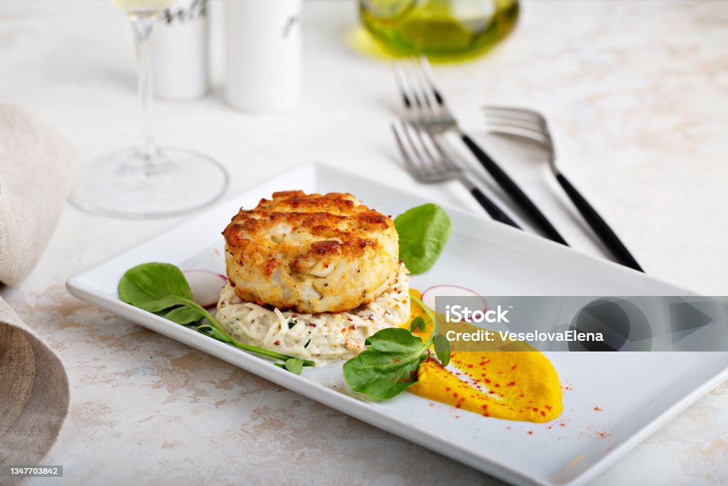 Gourmet plated fishcake with vegetables Gourmet plated fishcake or crabcake with vegetable puree, restaurant food Fish Cakes Stock Photo
