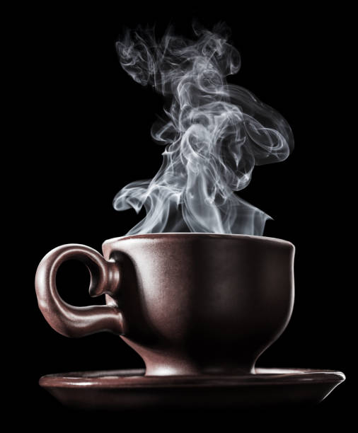 Brown ceramic cup of fresh steaming fragrant aromatic morning hot coffee over black background. Smoke from hot coffee.