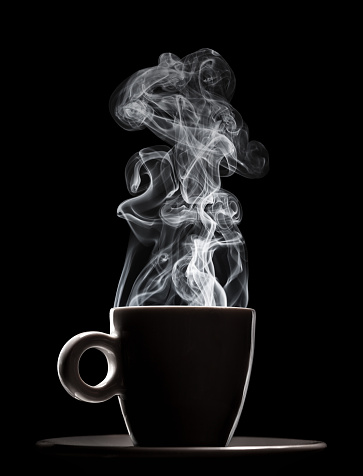 White ceramic cup of fresh steaming fragrant aromatic morning hot coffee over black background. Smoke from hot coffee.