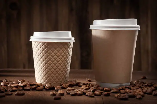 Hot Fresh Brewed Flavored Coffee. Two Classic Brown Papercups. On Vintage Wooden Background With Coffee Beans.