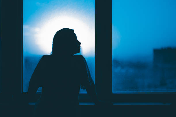 istock Woman in silhouette at window 1347703979