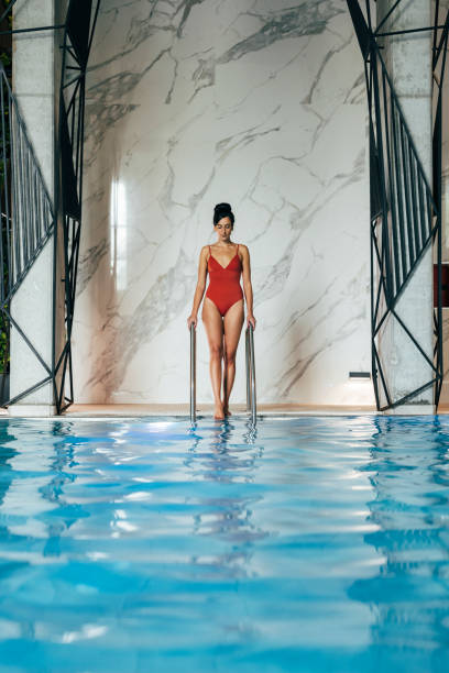 istock Beautiful Woman Getting Into a Swimming Pool 1347703994