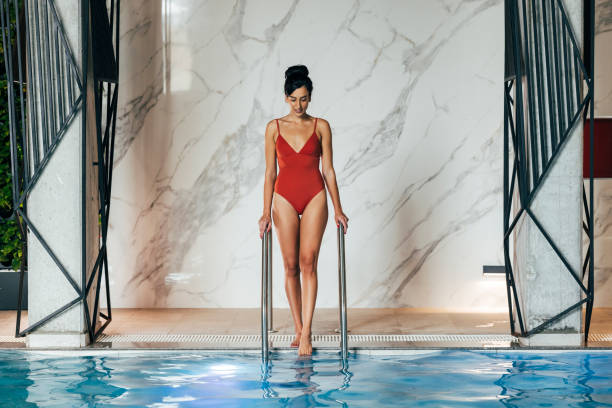 istock Beautiful Woman Getting Into a Swimming Pool 1347703997