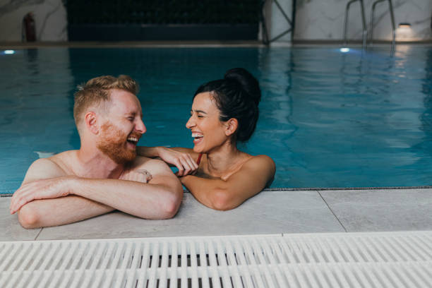 pareja feliz divirtiéndose en la piscina del hotel - heterosexual couple fotografías e imágenes de stock