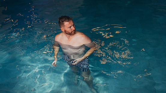 Handsome man in swimwear standing in the pool