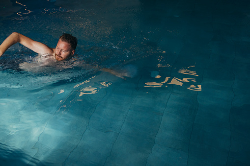 Handsome man in swimwear swimming in the pool