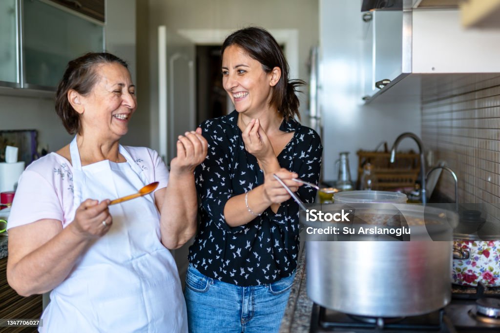 Elderly woman and her daughter are cooking ashura in the kitchen for the whole family and tasting it Ashura - Muharram Stock Photo