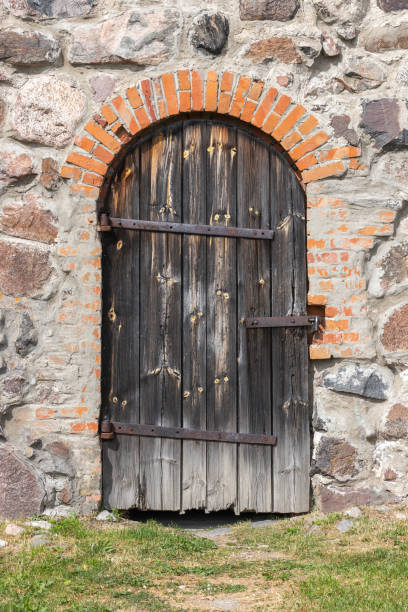 istock Old arched wooden door in a stone wall 1347710257