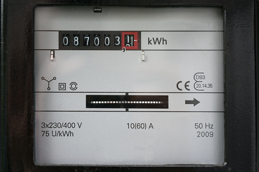 Electricity meter counting kilowatt hours consumed at home, concept of saving money on power consumption during rising energy prices, selected focus