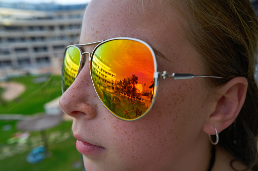 Girl profile with tropical palm trees reflected in the sunglasses