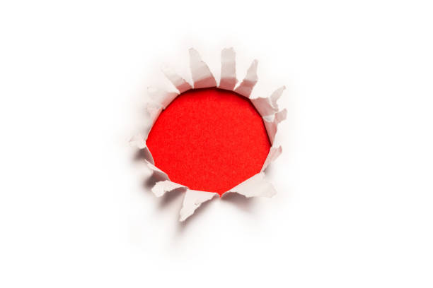 istock A hole in a white paper on a red background. 1347712497