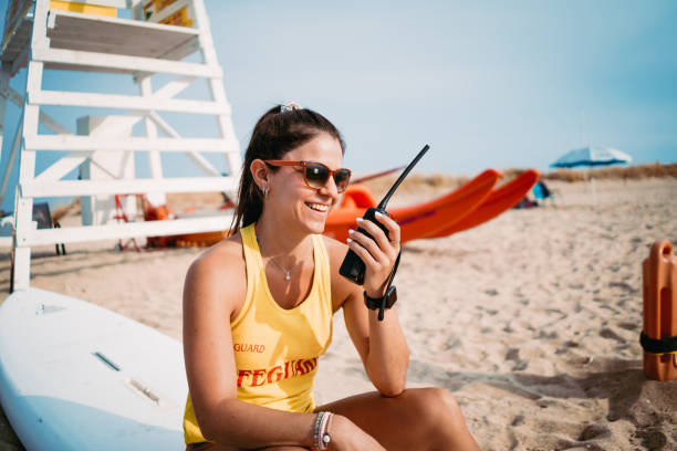 sauveteur utilisant son walky talky, radio - shorts rear view summer beach photos et images de collection