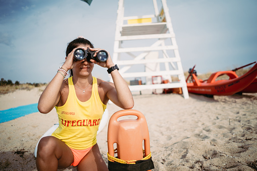 Female lifeguard with life buoy and binoculars
