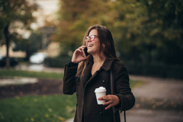 istock Beautiful young woman using smartphone and drinking coffee takeaway 1347714406