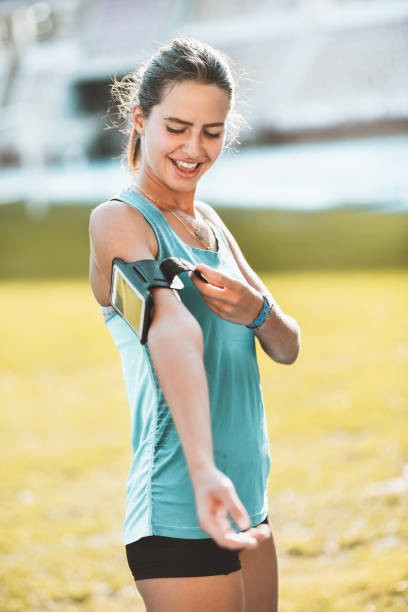 istock Female Athlete Attaching Smartphone To Arm While Running On Track 1347715116