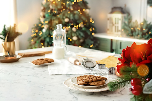 Christmas, New Year, DIY, holidays preparation and creativity concept. Getting ready to celebration. Gingerbread cookies on decorated kitchen near christmas tree.
