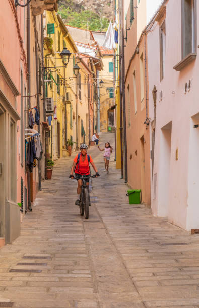Woman cycling in Rio Nell` Elba on the Island of Elba, italy nice active woman exploring the beautifull village of Rio Nell` Elba on the Island of Elba, Tuscan Arichipelago, Tuscany, Italy livorno stock pictures, royalty-free photos & images