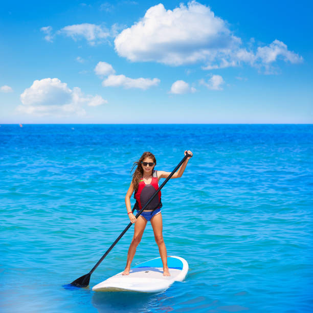istock Kid paddle surf surfer girl with row in the beach 1347719779
