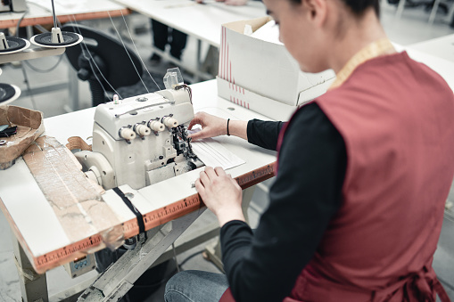 Tailor, woman hands and sewing machine for clothes fabric, luxury apparel or creative design in studio workshop atelier. Startup small business designer, service and sewer working on fashion outfit