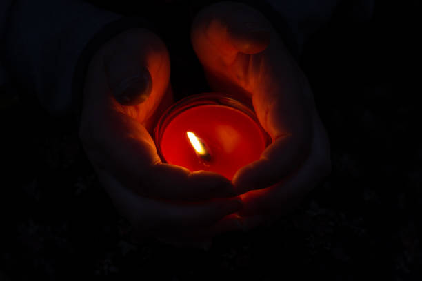 istock A red burning candle between a woman's palms. The woman shelters 1347720618