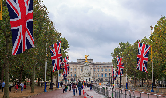 Buckingham Palace, London, 2021.  The Mall leading to the Palace and Queen Victoria Monumnet lined with Union Jack Flags and barriers.  Tourists have returned to the capital now that Covid restrictions are softened.