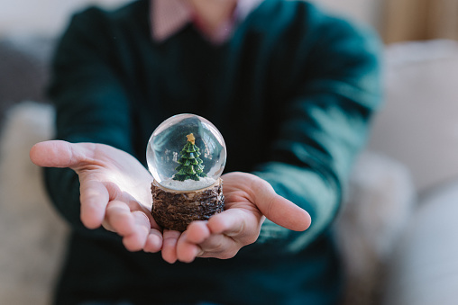 New Year's souvenir. A small fir-tree in a transparent sphere in hands of the person. Celebration Christmas concept.