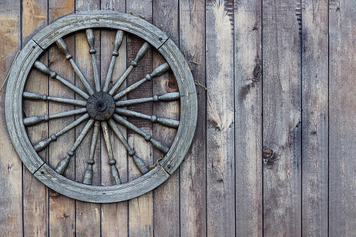 wheel of an old wooden cart on a wooden wall, use as a background