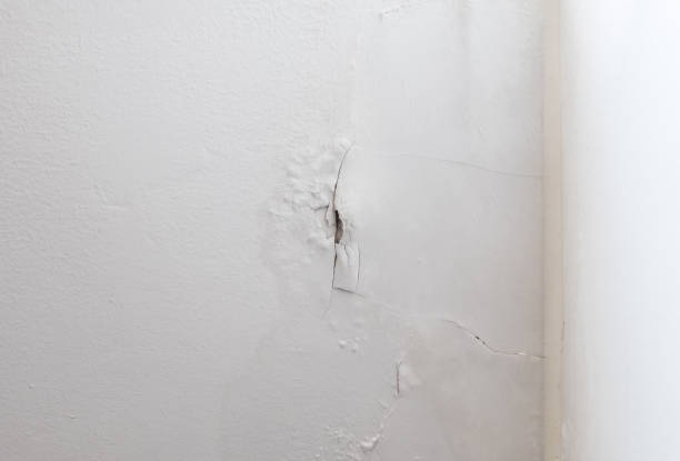 白いペンキの壁が剥がれ、寝室の隅近くに長い亀裂が入っています。 - peeling paint wall white ストックフォトと画像