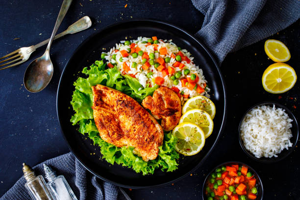 Fried chicken breast with white rice, green peas and carrots on black wooden table Fried chicken breast with white rice, green peas and carrots on black wooden table chicken fried steak stock pictures, royalty-free photos & images