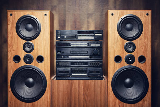 Retro Tiered Stereo System And Wood Speakers Vintage 1980s and 1990s audio sound equipment, complete with wood veneer.  Cassette tape deck, CD player, and tuner.  Wood paneling on wall in the background. stereo stock pictures, royalty-free photos & images