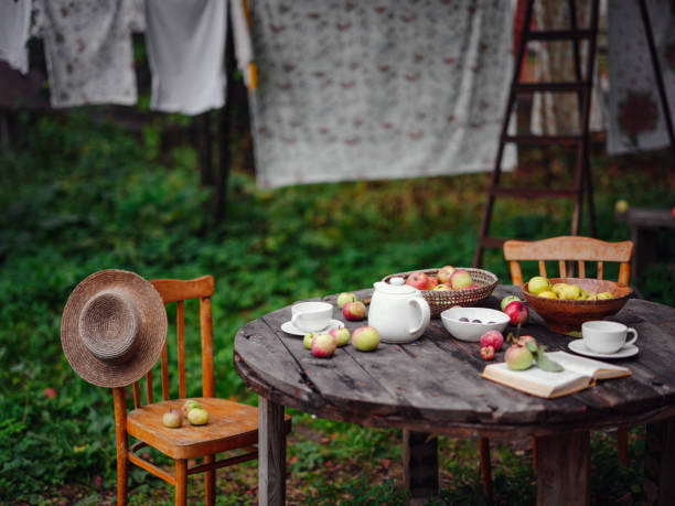 beautiful autumn still life in apple orchard, old table with cup, teapot, apples and book. Fall Getaway, Apple Picking and Harvest Day Celebration concept