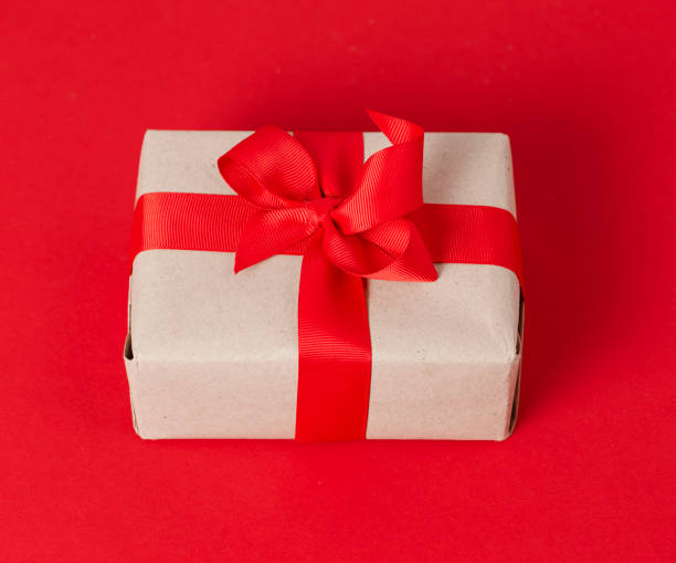 istock Gift box in craft paper on a red background with a red bow. 1347736480