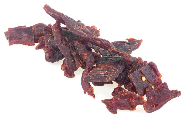 istock Portion of spiced beef jerky isolated on a white white background. Dried peppered beef jerky. 1347737123