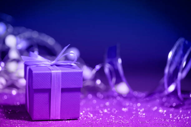 Close-up of a Christmas present (gift box) with defocused christmas lights and decorations in the background. Space for copy.