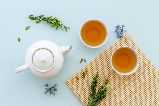 istock Black tea in cups with white teapot and green leaves 1347741556