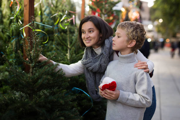 istock Happy tween boy with mother choosing Xmas tree at market 1347742227