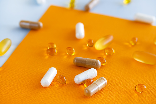 Yellow capsules of nutraceuticals in spoon. Pills and meds.
