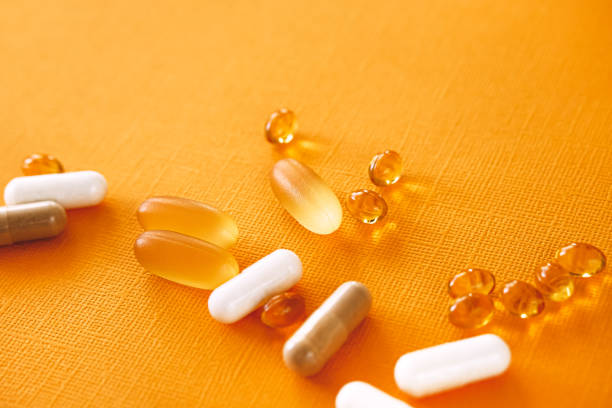 cápsulas amarillas de nutracéuticos en cuchara. pastillas y medicamentos. - vitamin pill nutritional supplement capsule lecithin fotografías e imágenes de stock