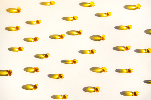 Yellow capsules of nutraceuticals in spoon. Pills and meds.