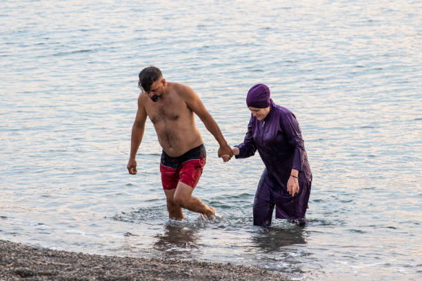 muslim man and woman come out of the sea. - 回教泳裝 圖片 個照片及圖片檔