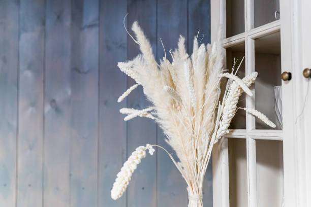 Bush of dry grass in basket decorated at cafe against wooden wall background. elegante arbusto de hierba seca en cesta decorada en la cafetería contra fondo de pared de madera.paquete de orejas. espigas doradas de trigo en florero.decoración del hogar. decoración natural ecológica del hogar con ramo de centeno salvaje.