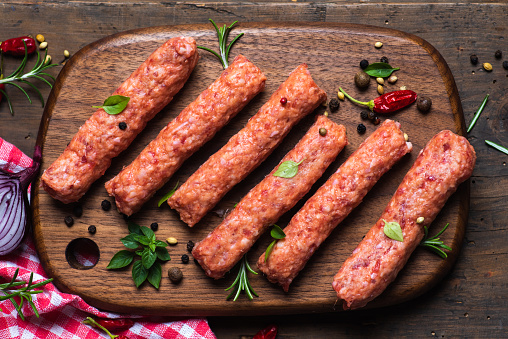 fresh minced beef and pork kebabs with fresh spice fresh minced beef and pork kebabs with fresh spices, on a wooden cutting board and wooden brown background. Top views