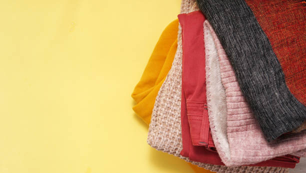 istock Yellow background. Clean woolen clothes in stack, top view. Stack of knitted warm clothes on yellow background Autumn, winter season knitwear. 1347752514