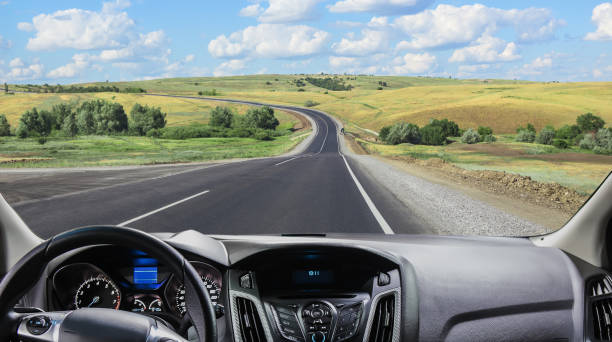 View from the windshield of a car driving along a sunset road