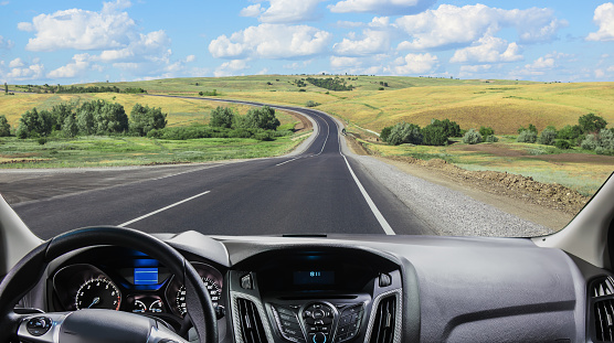 View from the windshield of a car driving along a sunset road on the horizon