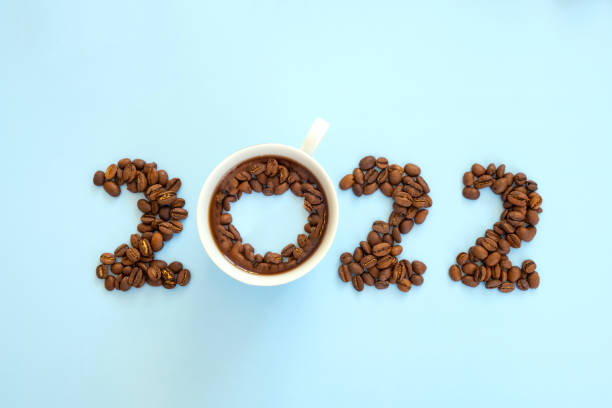 2022 Coffee Beans 2022 number made of coffee beans and cup of coffee on light blue background as symbol of new resolution and start. Happy New Year and Merry Christmas. new years day photos stock pictures, royalty-free photos & images