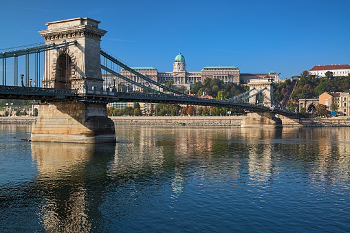 Budapest, Hungary - October 4, 2015: Szechenyi Chain Bridge across Danube and Royal Palace in Buda Castle in sunny autumn morning. Buda Castle is the historical castle and palace complex of the Hungarian kings. The present palace was built in 1749-1769. The bridge was constructed in 1840-1849.