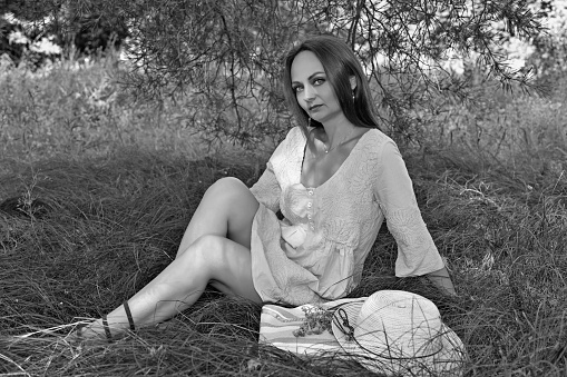 Young woman in a blue dress in a clearing in the forest.