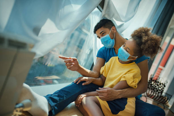 istock Father and daughter sitting by a window during coronavirus quarantine. 1347768446